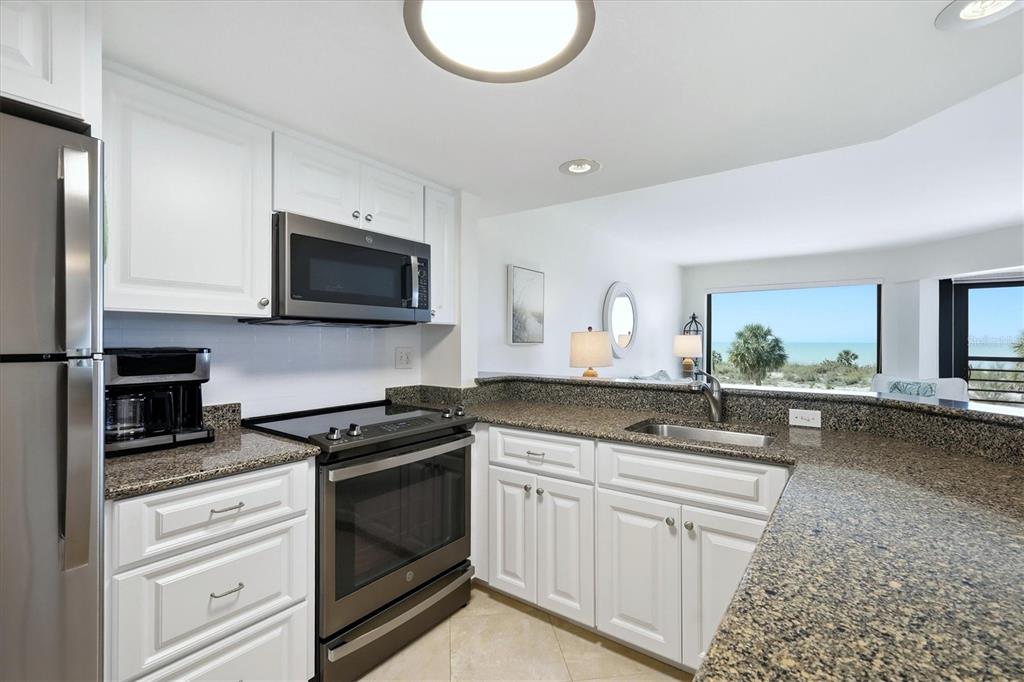 5000 Gasparilla Road, Unit BC205 Boca Grande, FL 33921 - Photo 12 of 50 a kitchen with granite countertop a sink a stove and cabinets