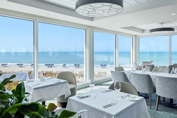 a dining hall with furniture a table and kitchen view