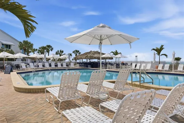 a view of a swimming pool with a table and chairs under an umbrella