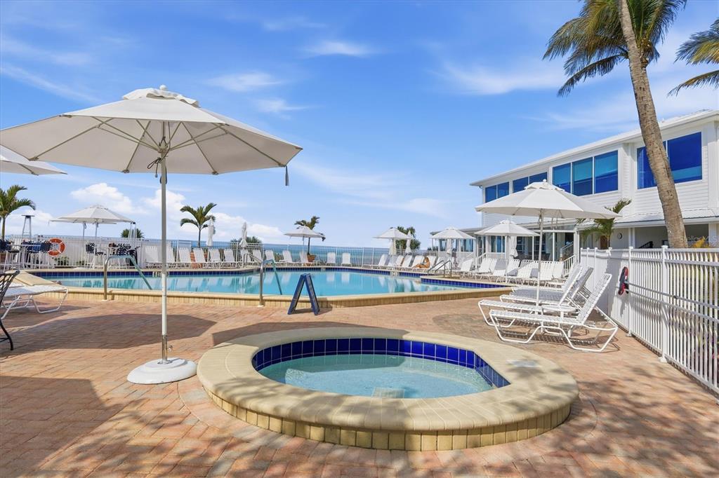 5000 Gasparilla Road, Unit BC205 Boca Grande, FL 33921 - Photo 32 of 50 a view of a swimming pool with a table and chairs under an umbrella