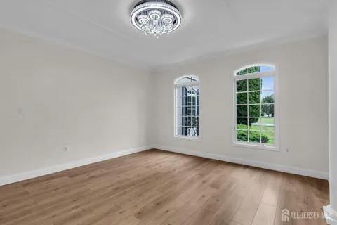 an empty room with wooden floor fan and windows