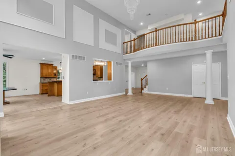 a view of an empty room with wooden floor and windows