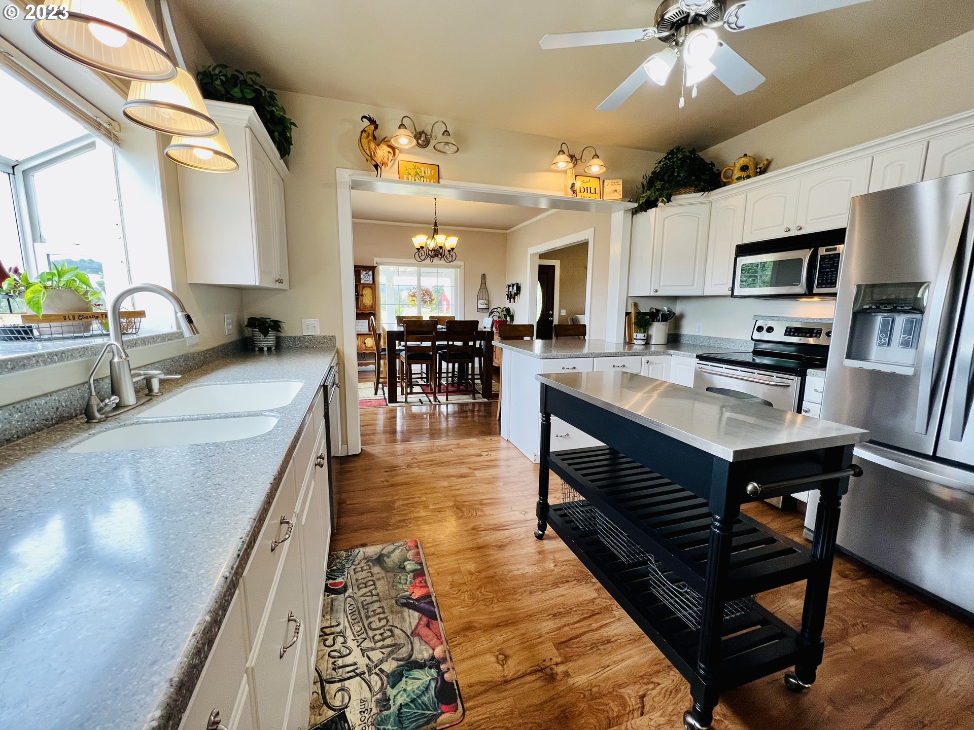 5393 Nonpareil Road Sutherlin, OR 97479 - Photo 10 of 42 a kitchen with stainless steel appliances granite countertop a stove top oven a sink a dining table and chairs with wooden floor