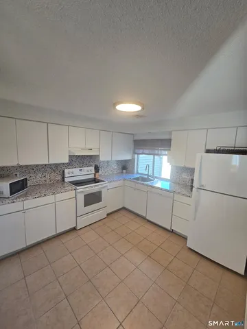 a kitchen with white cabinets and white appliances
