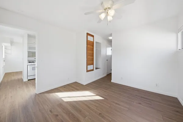 an empty room with wooden floor chandelier fan and windows