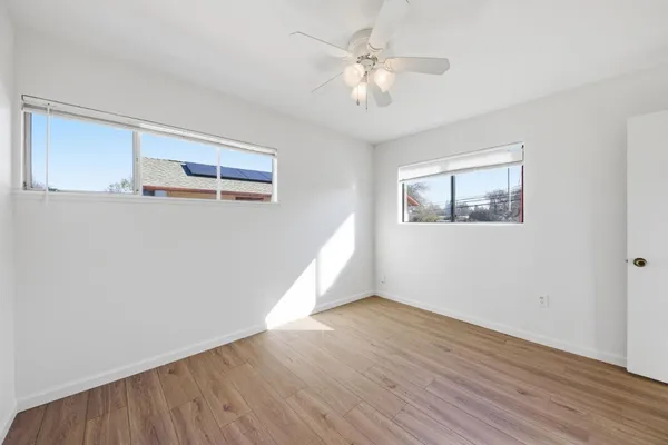 a view of an empty room with wooden floor and a window