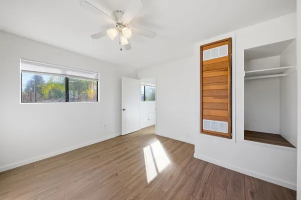 a view of an empty room with wooden floor and a window