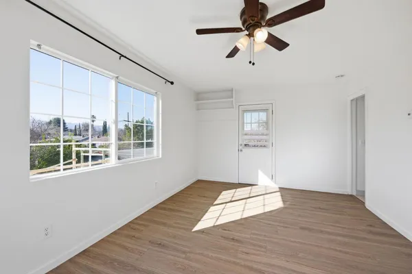 a view of empty room with wooden floor and fan