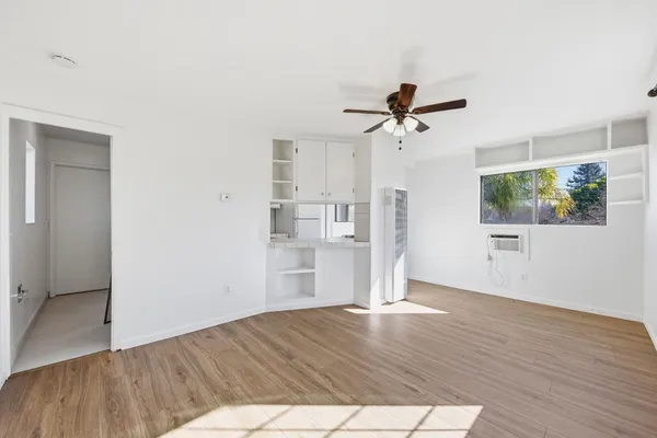 a view of a room with wooden floor a ceiling fan and windows
