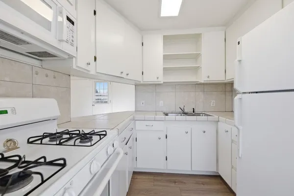 a kitchen with sink a stove and white cabinets