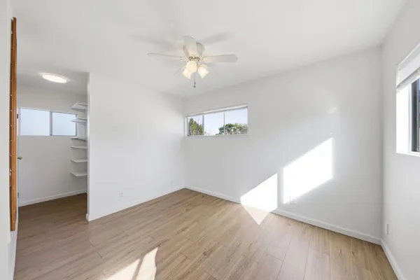 a view of empty room with wooden floor and fan