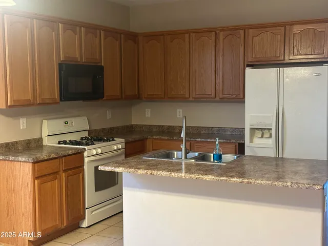a kitchen with granite countertop a stove a sink and a microwave