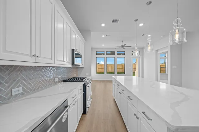 a large kitchen with stainless steel appliances granite countertop a sink and dishwasher with white cabinets