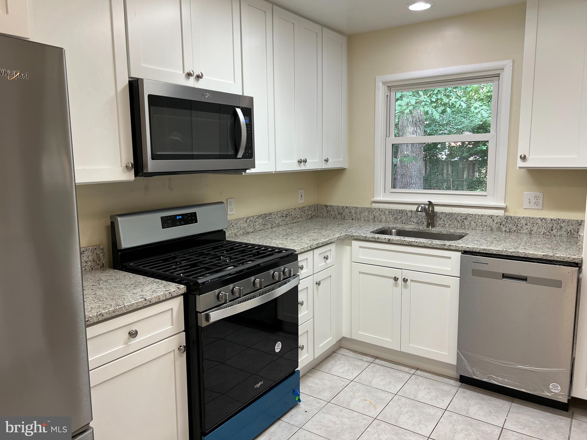 5626 Heming Avenue Springfield, VA 22151 - Photo 15 of 53 a kitchen with granite countertop white cabinets appliances and a window