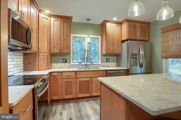 a kitchen with stainless steel appliances granite countertop a refrigerator a sink a stove a dining table and chairs
