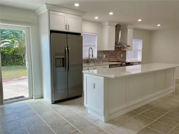 a kitchen with kitchen island granite countertop a refrigerator and a sink