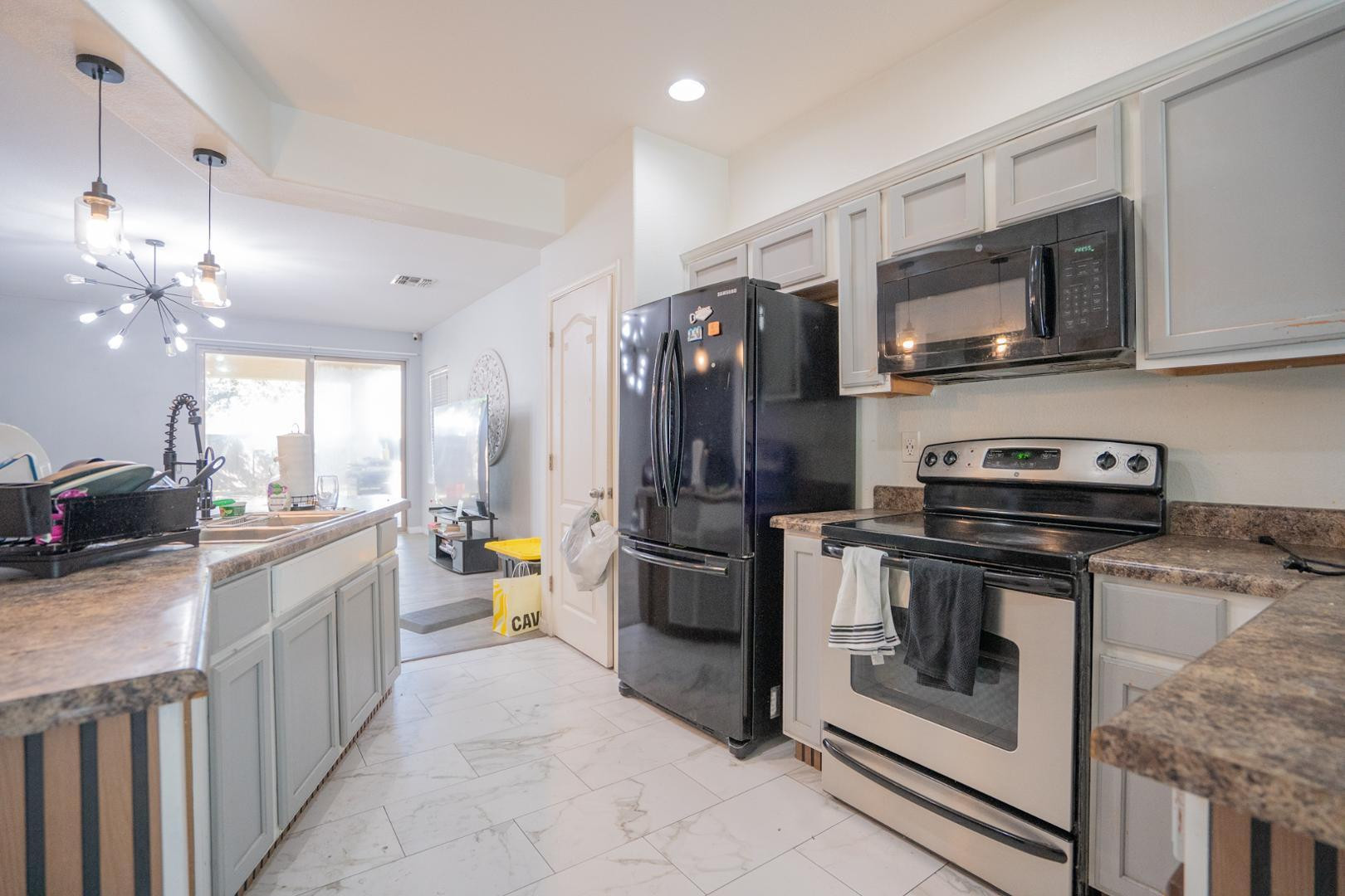 9377 West Milkweed Loop Phoenix, AZ 85037 - Photo 4 of 28 a kitchen with stainless steel appliances a stove microwave and refrigerator