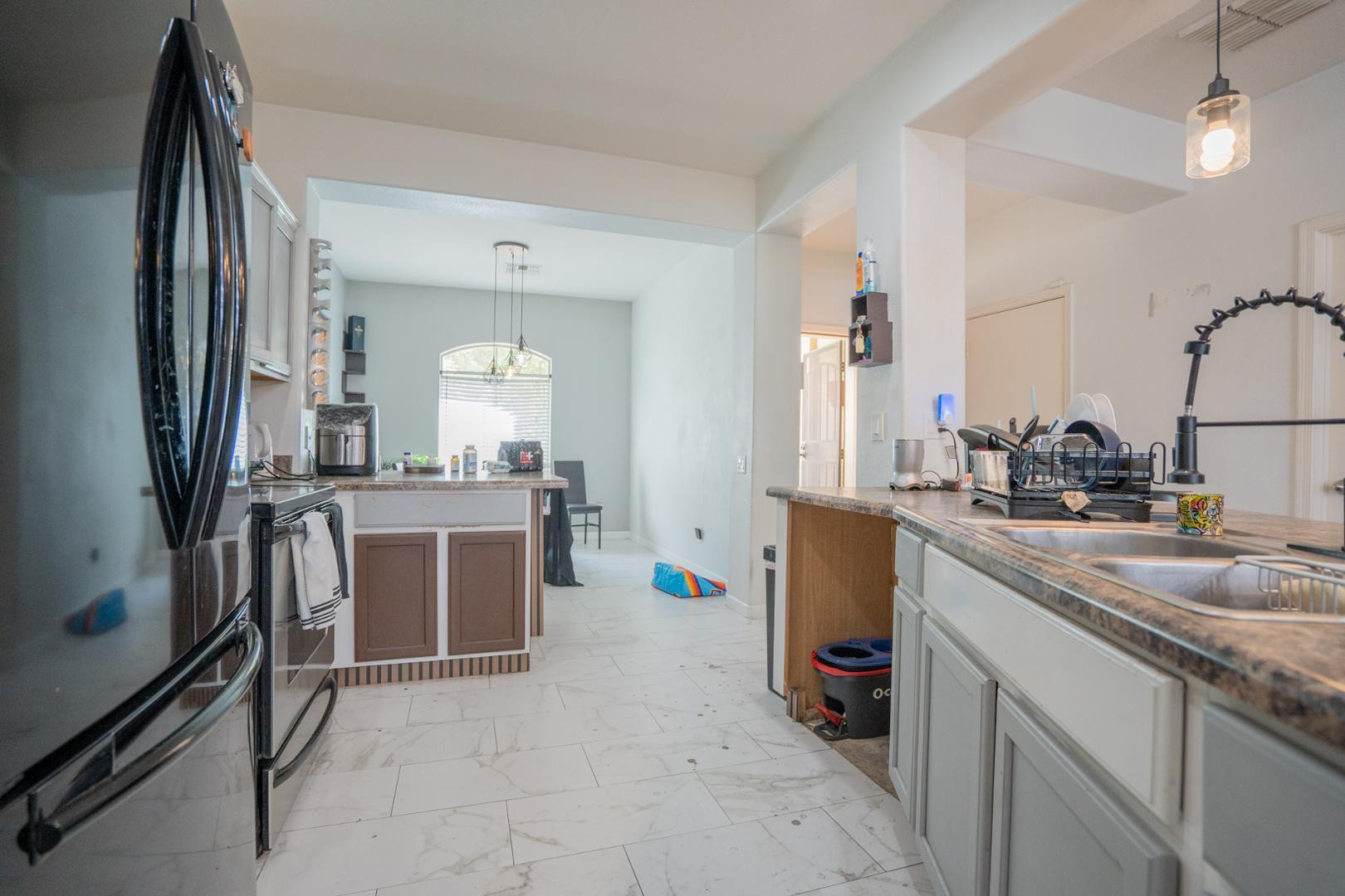 9377 West Milkweed Loop Phoenix, AZ 85037 - Photo 5 of 28 a kitchen with a sink refrigerator and microwave