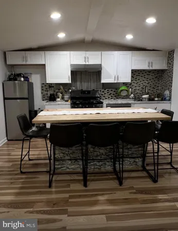 a kitchen with stainless steel appliances granite countertop a stove a sink white cabinets and chairs