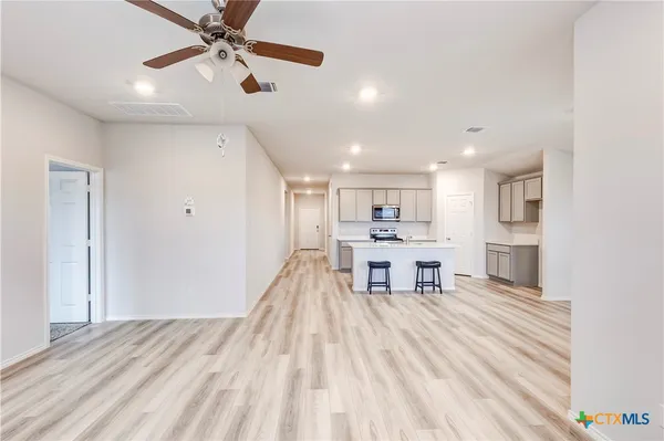a view of a kitchen with kitchen island stainless steel appliances wooden floor dining table and chairs