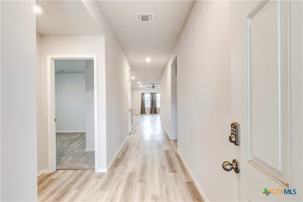 a view of a hallway with wooden floor and a bathroom