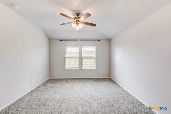 an empty room with windows and chandelier fan