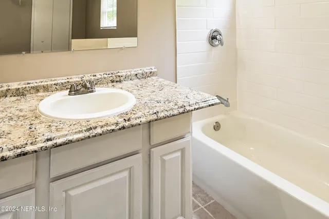 a bathroom with a granite countertop sink and a bathtub