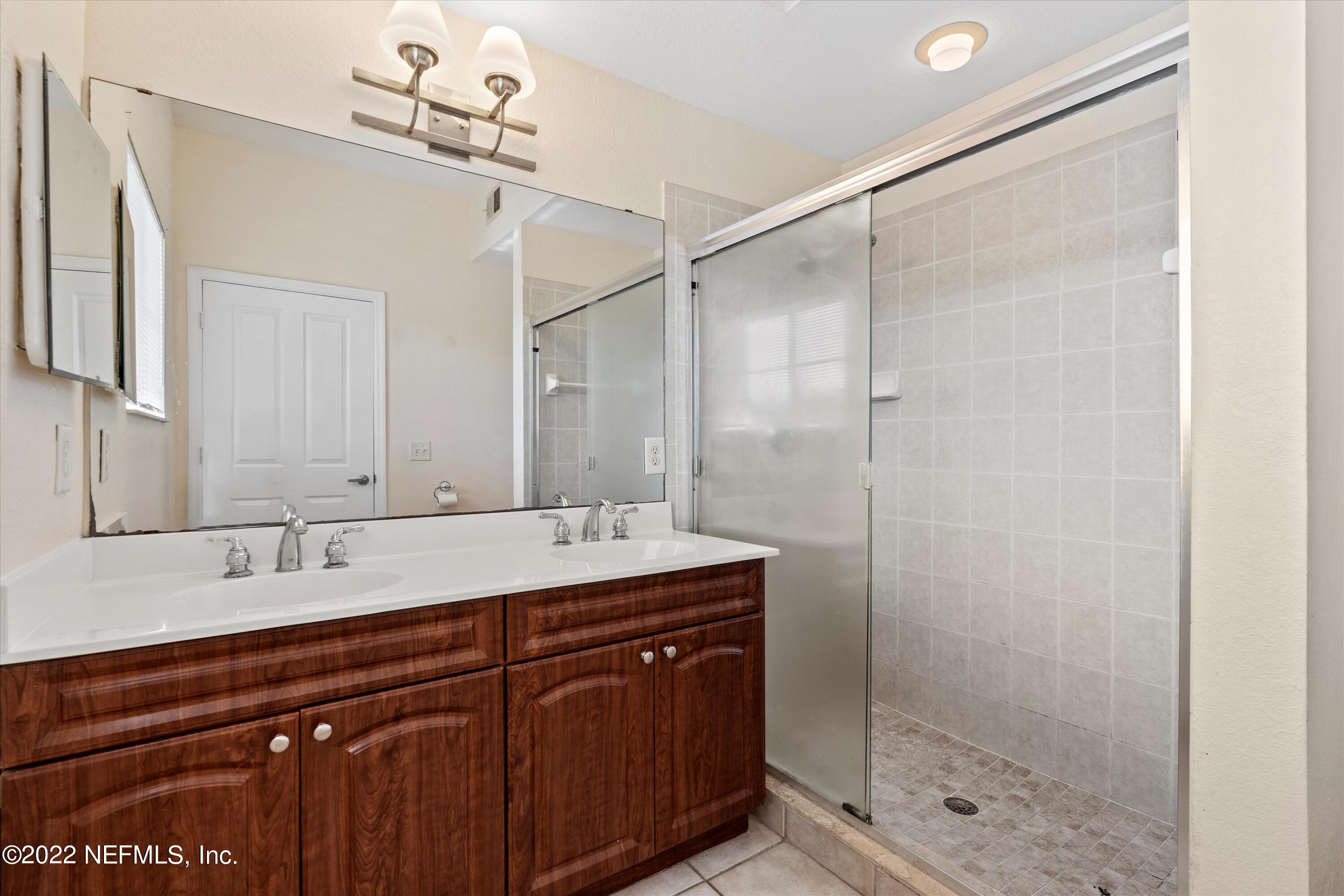 9745 Touchton Road, Unit 3203 Jacksonville, FL 32246 - Photo 14 of 30 a bathroom with a shower sink vanity granite and mirror