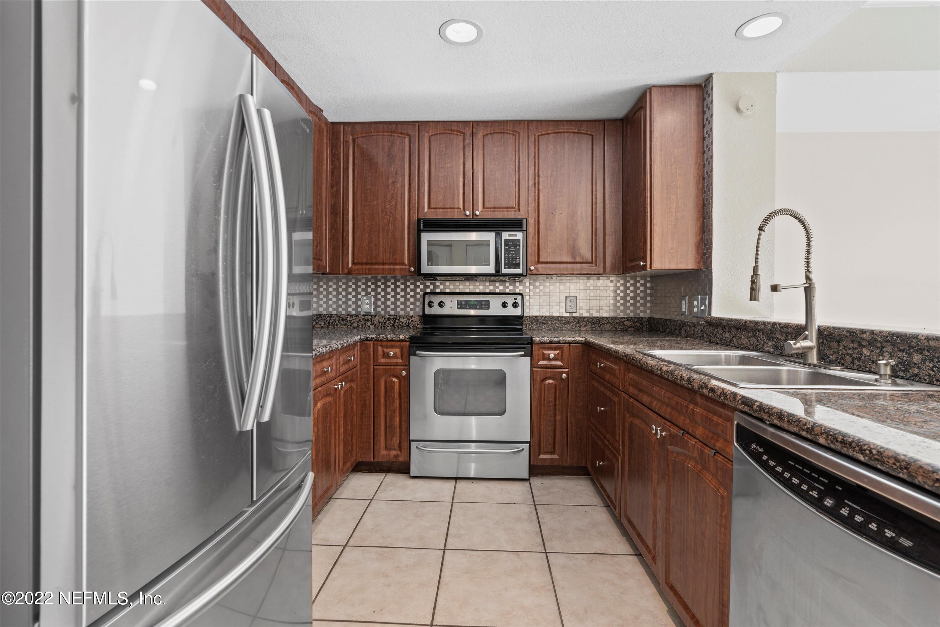 9745 Touchton Road, Unit 3203 Jacksonville, FL 32246 - Photo 6 of 30 a kitchen with granite countertop a refrigerator and a stove top oven