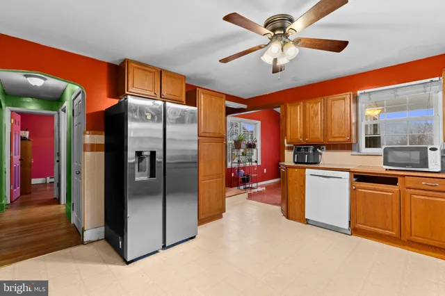 a kitchen with stainless steel appliances granite countertop a refrigerator a oven and a sink with wooden floor