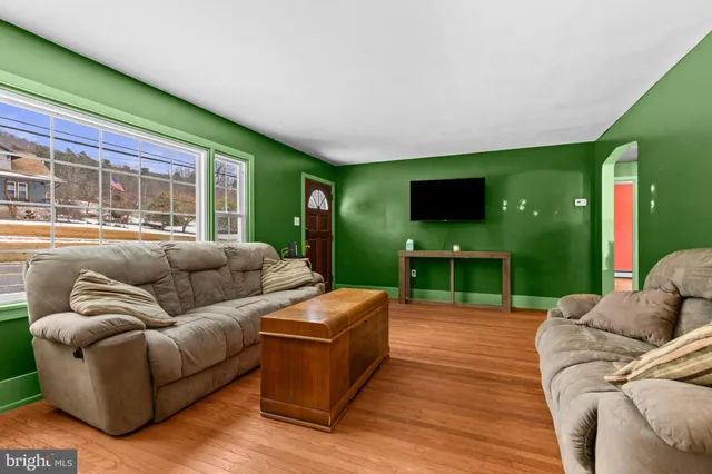 a living room with furniture a flat screen tv and floor to ceiling window