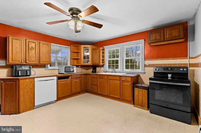 a kitchen with stainless steel appliances granite countertop a stove top oven a sink dishwasher a dining table and chairs with wooden floor