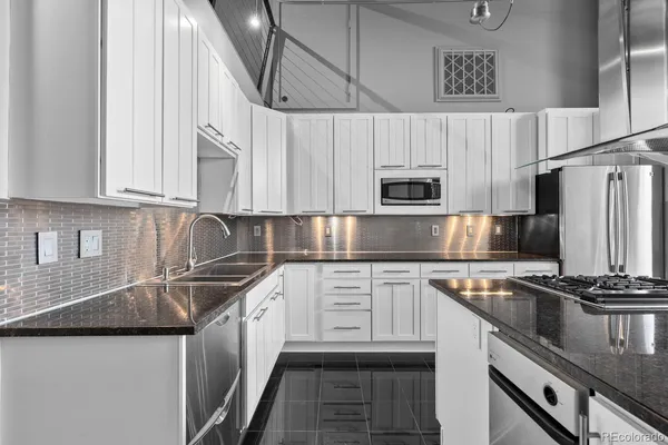 a kitchen with stainless steel appliances granite countertop a table chairs stove and white cabinets