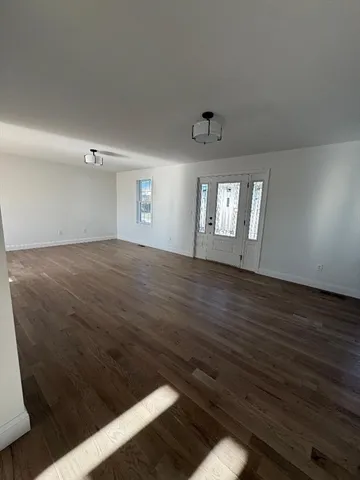 a view of an empty room with window and wooden floor
