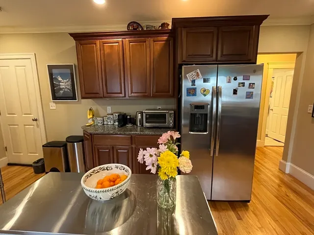 a kitchen with stainless steel appliances granite countertop a refrigerator a stove and a wooden floor