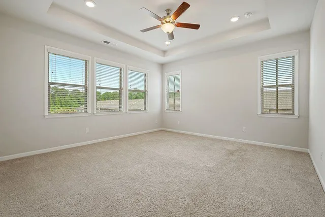 an empty room with chandelier fan and windows