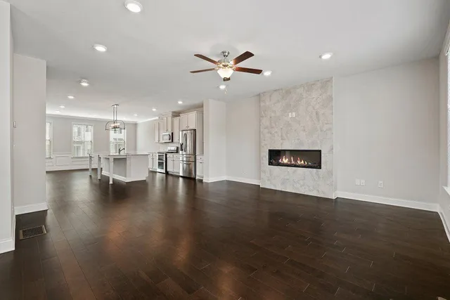 a view of an empty room with wooden floor and a ceiling fan