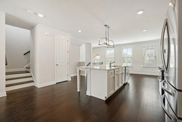 a kitchen with stainless steel appliances a refrigerator a sink dishwasher a stove and white cabinets with wooden floor