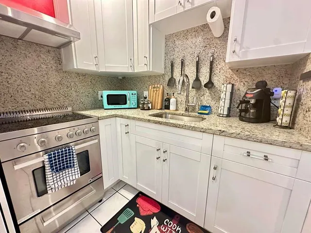 a kitchen with granite countertop white cabinets and white appliances
