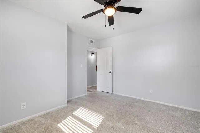 an empty room with a ceiling fan and carpet
