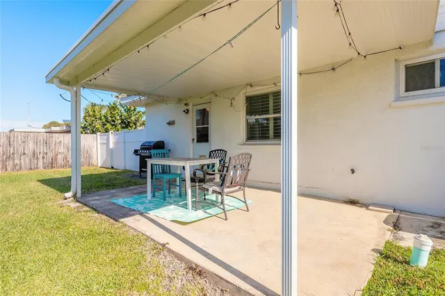 a view of a backyard with table and chairs and a barbeque