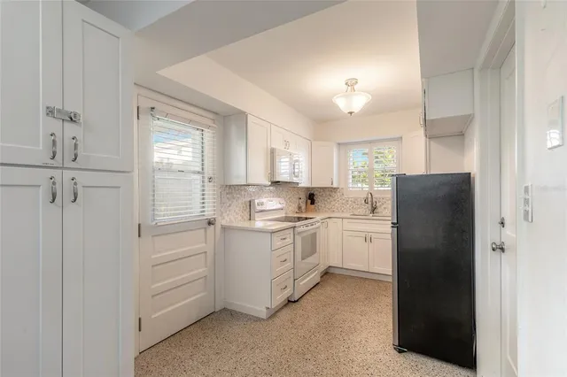 a kitchen with a refrigerator stove and white cabinets