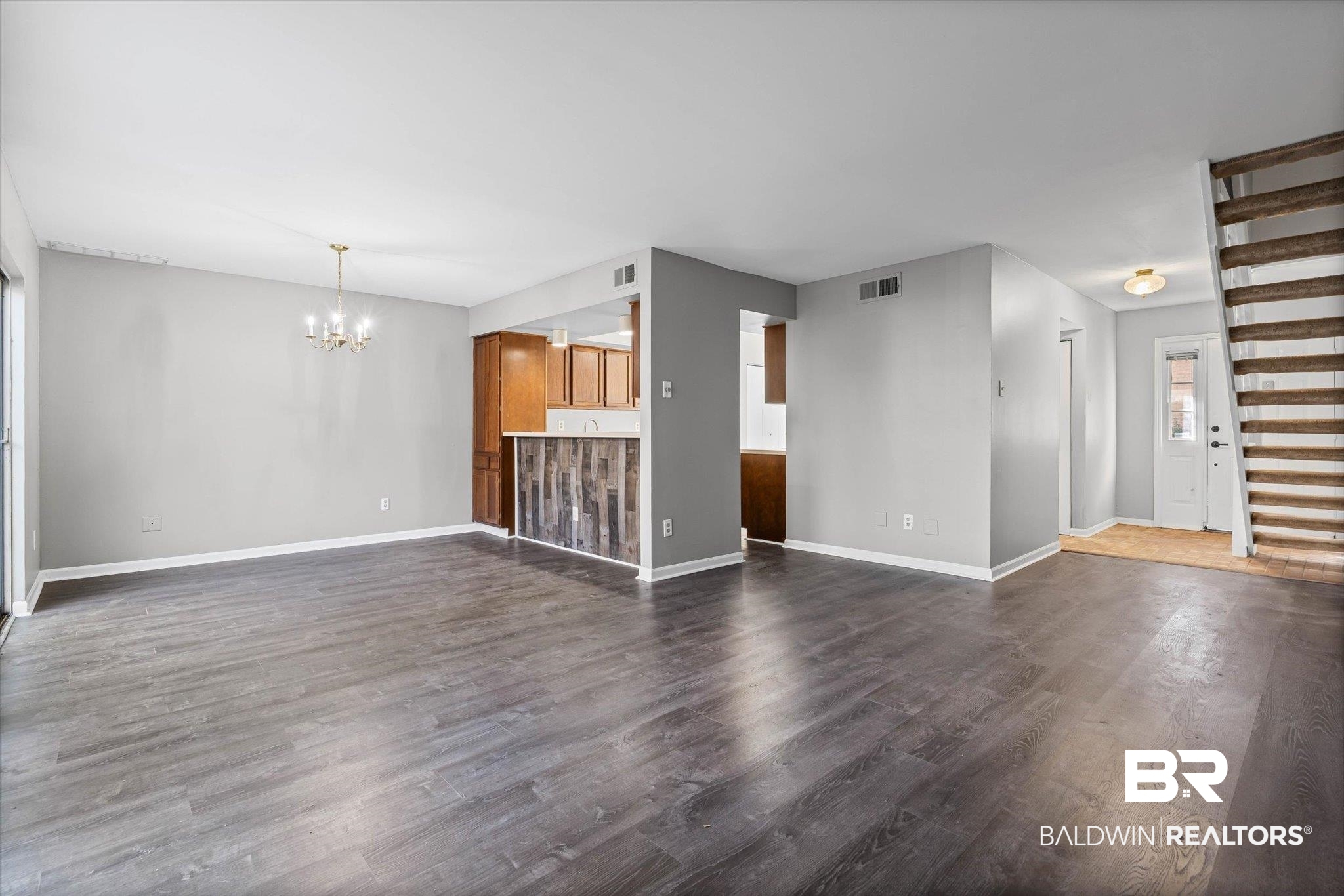 6701 Dickens Ferry Road, Unit 100 Mobile, AL 36608 - Photo 6 of 24 Unfurnished living room featuring dark wood-style flooring and a chandelier