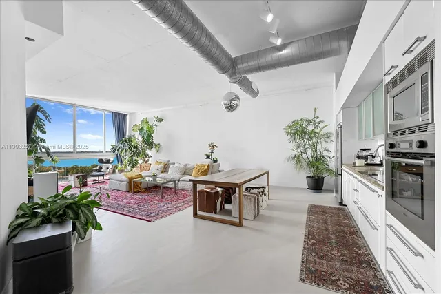 a living room with furniture a potted plant and kitchen view