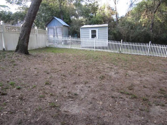 a view of a house with a small yard and a large tree