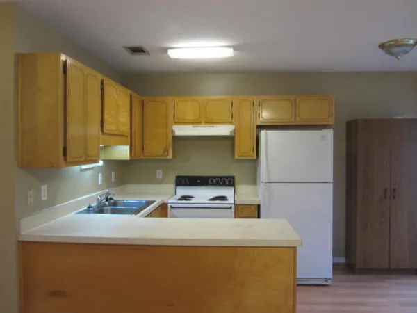 a kitchen with kitchen island a stove a refrigerator a sink and dishwasher with wooden floor