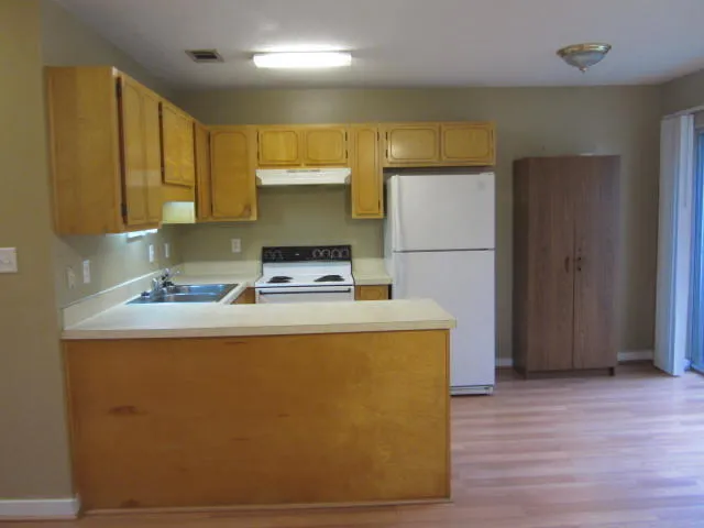 a kitchen with stainless steel appliances a refrigerator a sink and wooden floors