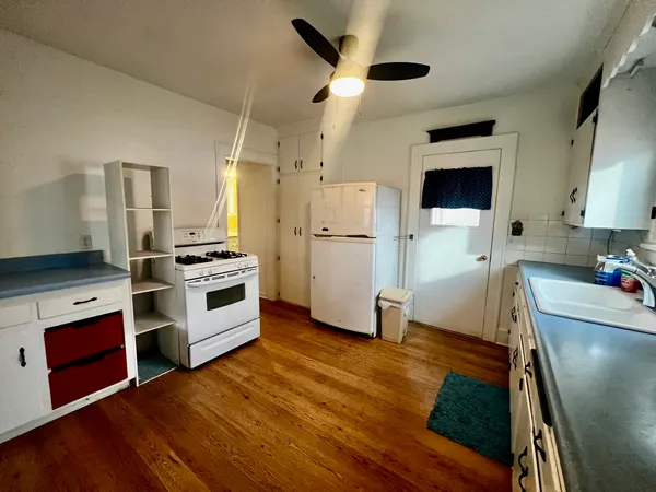 a kitchen with stainless steel appliances a stove a refrigerator a sink a oven with wooden floor