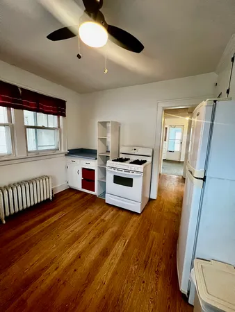 a kitchen with stainless steel appliances granite countertop a refrigerator a stove a sink and white cabinets with wooden floor