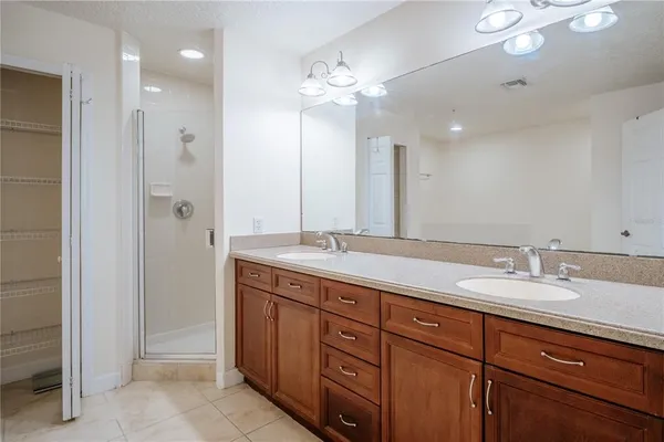 a bathroom with a granite countertop double vanity sink a mirror and shower